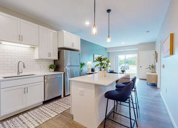 A kitchen with white cabinets and a blue chair.