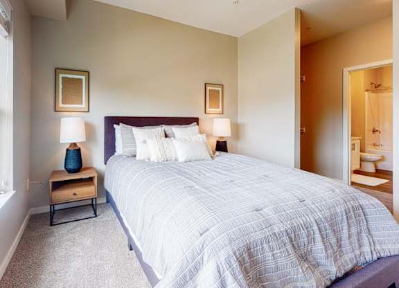 A bedroom with a large bed and a window overlooking a green lawn.