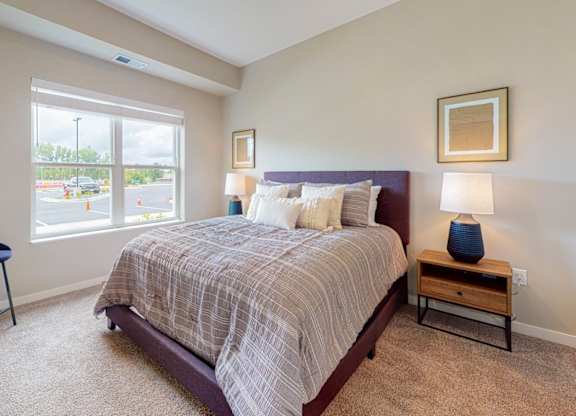 A bedroom with a bed, chair, and window.