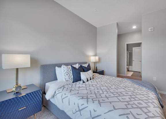 A bedroom with a large bed and a nightstand with a lamp.