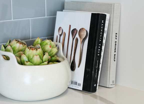 a close up of a white vase with a green plant in it next to a book