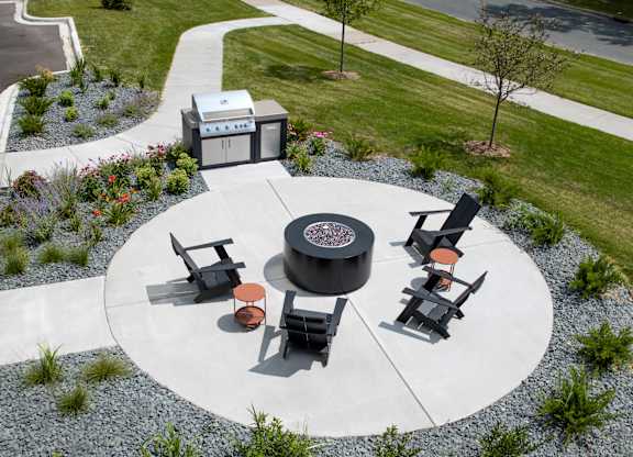 a fire pit and seating area on a concrete patio in a park