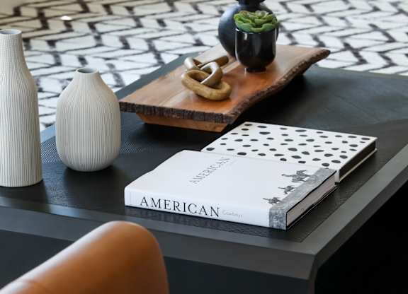 a black coffee table with a black and white geometric rug on top