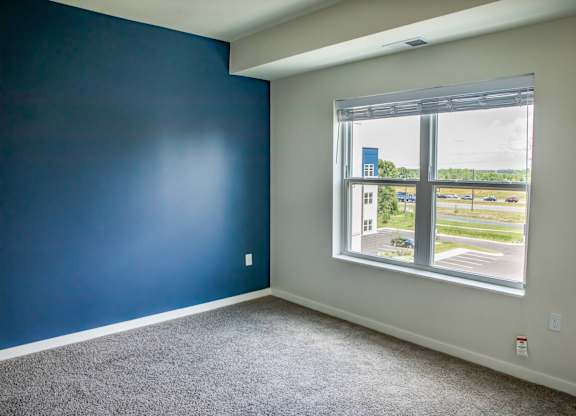 a bedroom with a large window and carpeted flooring