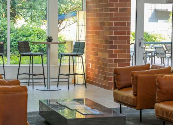 A room with a glass table and leather chairs.