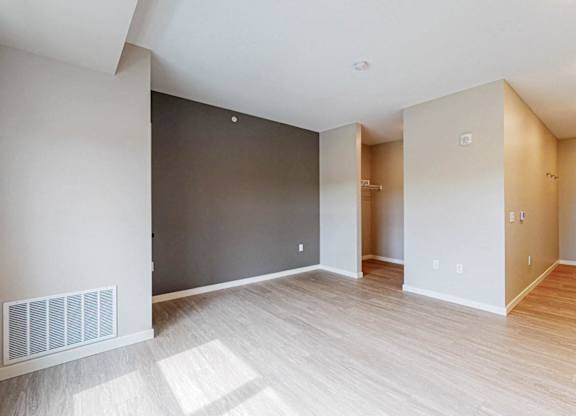 A spacious room with wooden flooring and white walls.