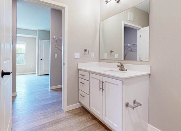 A white bathroom with a sink, mirror, and bathtub.
