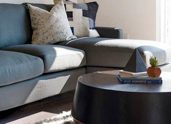 A grey couch with a white lamp above it.