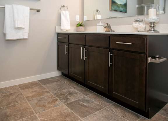 A bathroom with a brown cabinet and a tiled floor.