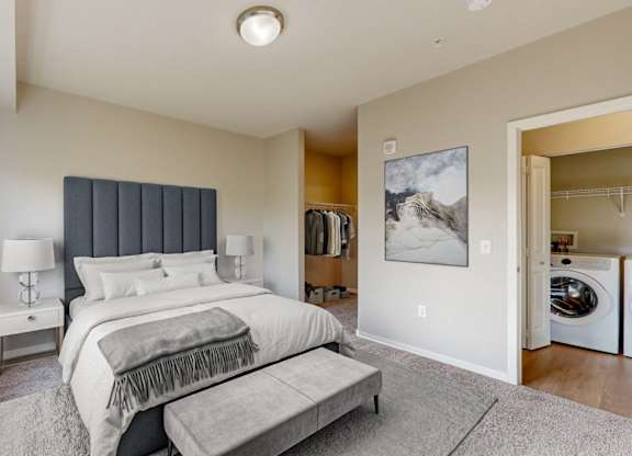 A bedroom with a large bed and a washing machine in the laundry area.