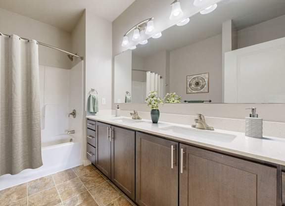 A bathroom with a shower curtain, two sinks, and a large mirror.