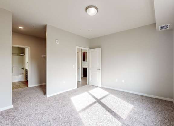 A spacious room with a carpeted floor and a window on the right side.