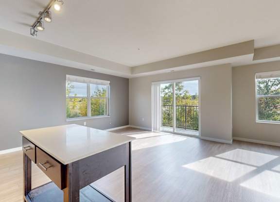 A spacious room with a table and chairs in the foreground and sliding glass doors leading to a balcony.