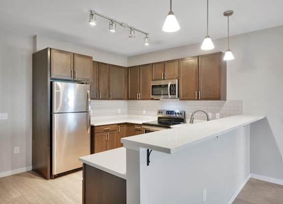 A kitchen with a white counter and wooden cabinets.