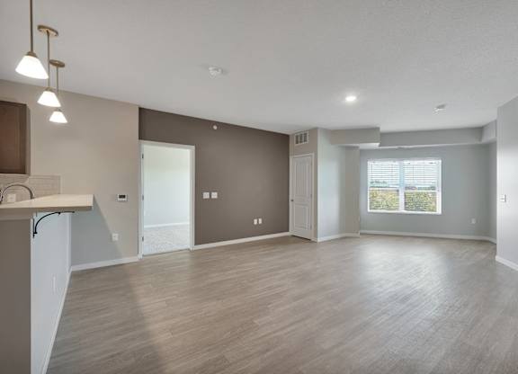 A spacious living room with a kitchenette and a view of the outdoors.
