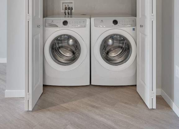 A laundry room with two washing machines and a white door.