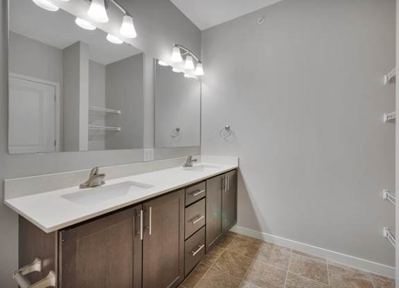 A bathroom with a sink, mirror, and lighting fixtures.