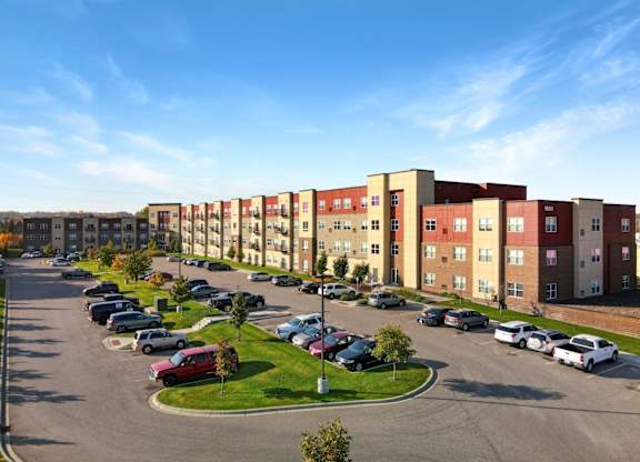 A parking lot in front of a row of apartment buildings.