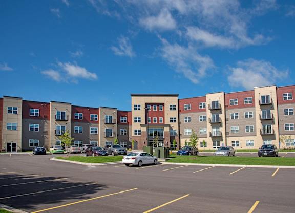 A parking lot in front of a multi-story apartment building.