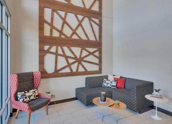 A living room with a grey couch, a red chair and a wooden wall panel.