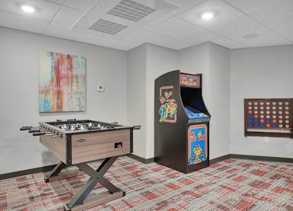 A room with a pool table, a pinball machine, and a painting on the wall.