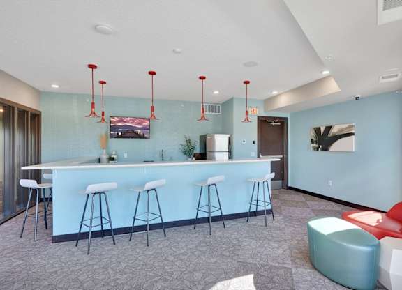 A bar area with white stools and a counter.