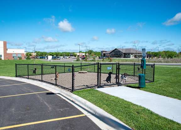 A parking lot with a black fence and a green trash can.