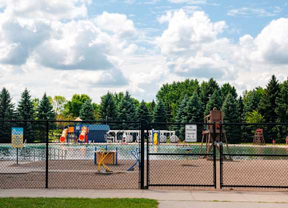 A playground with a fence and a sign in the background.