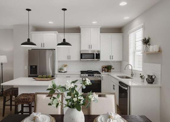 A modern kitchen with a dining table set for two.