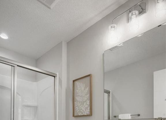 A white bathroom with a toilet, sink, and a mirror.