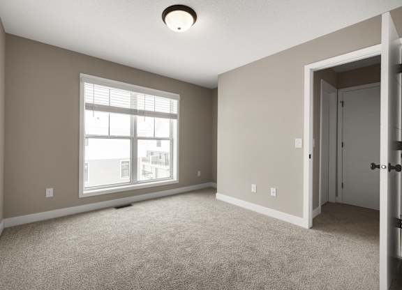 A room with a carpeted floor, a window, and a door.