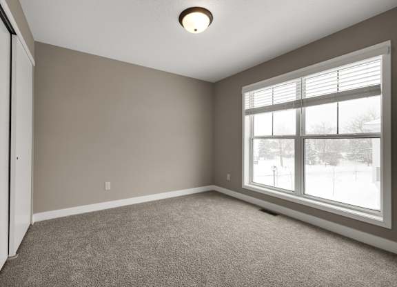 A room with a carpeted floor and a window.