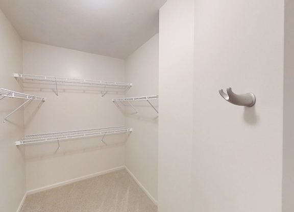 a spacious walk in closet with white walls and shelves