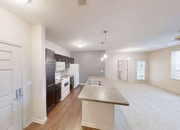 an open kitchen and living room with a sink and refrigerator