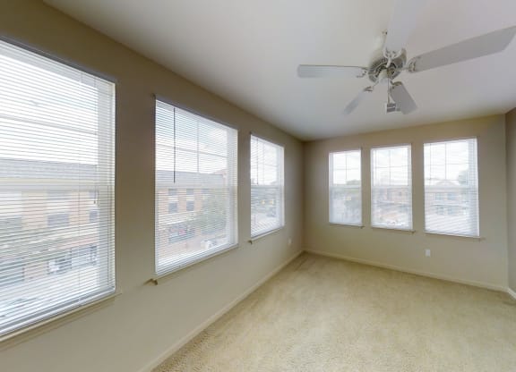 an empty living room with windows and a ceiling fan