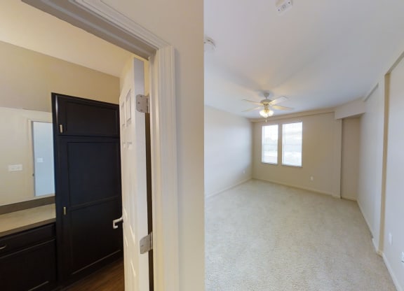 an empty living room with a ceiling fan and a window