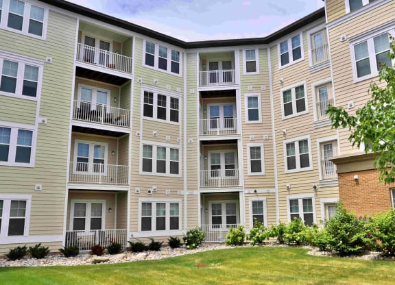 an exterior view of an apartment building with a green yard
