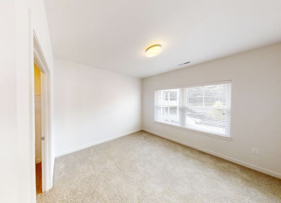 an empty bedroom with a large window and a door to a closet