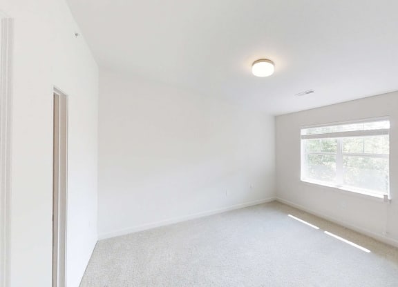 an empty room with a window and white walls