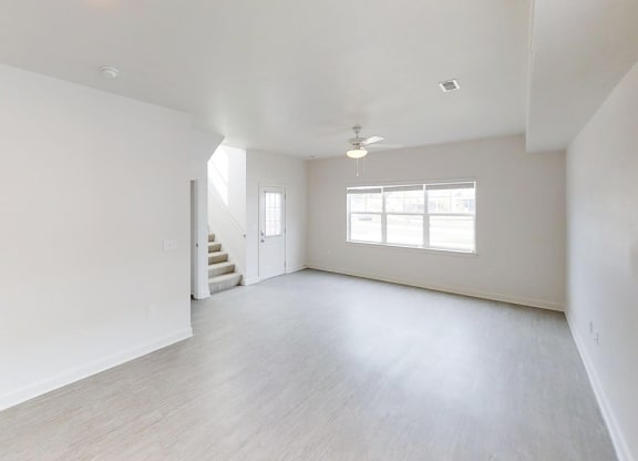 an empty living room with white walls and a staircase