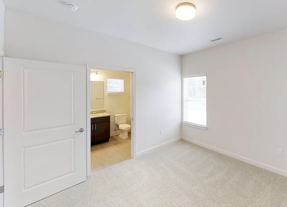an empty bedroom with a door to the bathroom