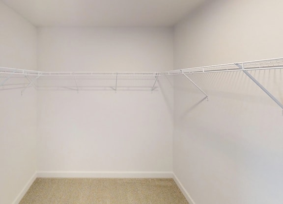 an empty closet with white walls and a wire rack