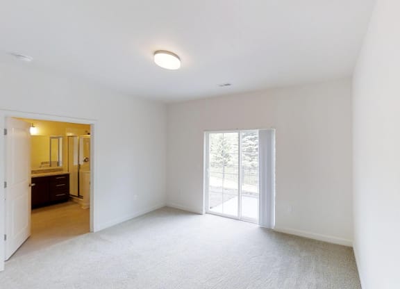 an empty living room with white walls and a sliding glass door