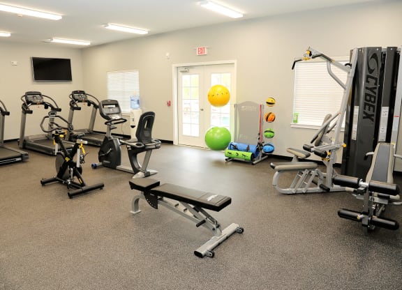 a gym with exercise equipment and a yellow ball in the corner