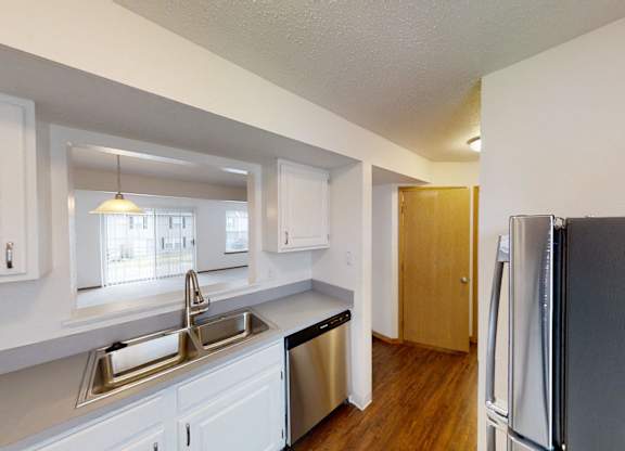 A kitchen with white cabinets and a black fridge.