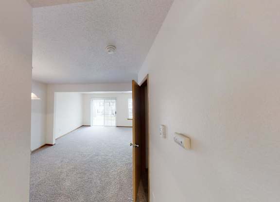 A hallway with a carpeted floor and white walls.