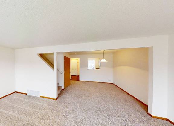 A room with a carpeted floor and a staircase leading to another room.