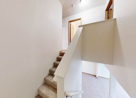A staircase with a beige carpeted runner and white balusters.