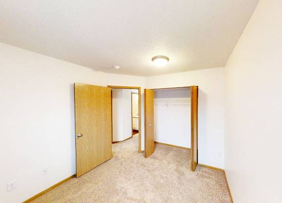 A room with a carpeted floor and two open doors.