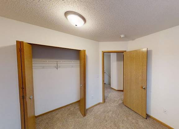 A room with two open doors and carpeted flooring.